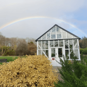 Glasshouse with a rainbow overhead in the sky