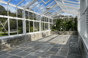 The interior of the glasshouse at Vandeleur Walled Garden & Visitor Centre. Glasshouse garden bed at the end of the room with benches in the foreground.
