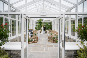 Glasshouse wedding ceremony at Vandeleur Walled Garden, with natural light and garden views.