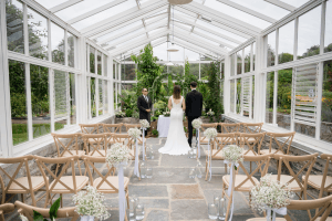 Bride and groom exchanging vows in the glasshouse wedding ceremony with celebrant present.